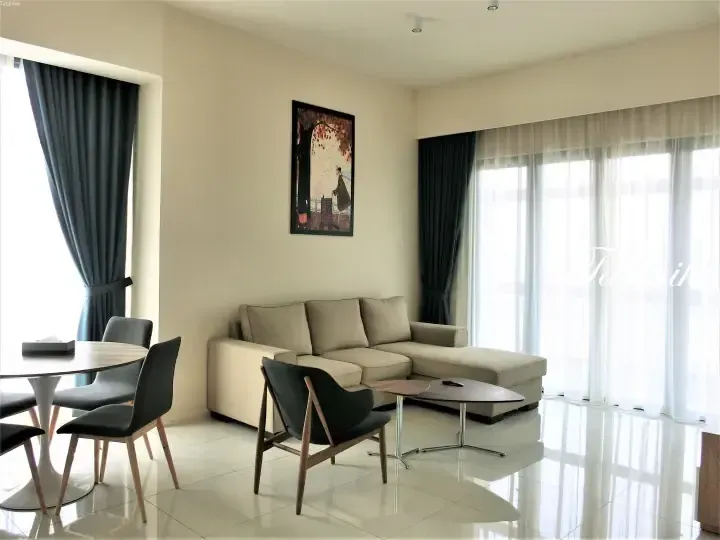 Modern living room with beige L-shaped sofa, dark grey curtains, and dining area in a bright apartment.