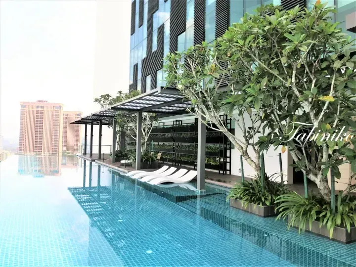Rooftop infinity pool with lounge chairs and greenery, overlooking Berjaya Times Square in Kuala Lumpur.
