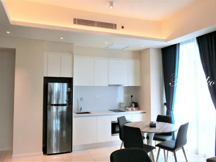 Modern kitchen with white cabinets, stainless steel fridge, and dining table in a Kuala Lumpur serviced residence