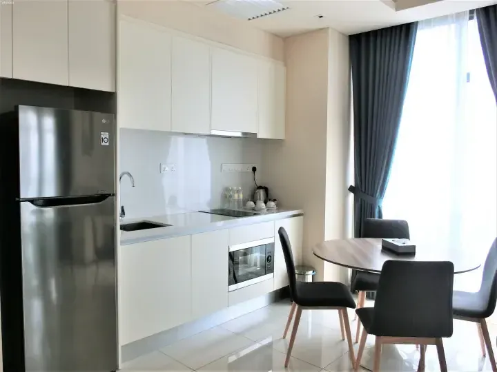 Modern kitchen with white cabinets, stainless steel LG refrigerator, and dining table near window in a serviced residence