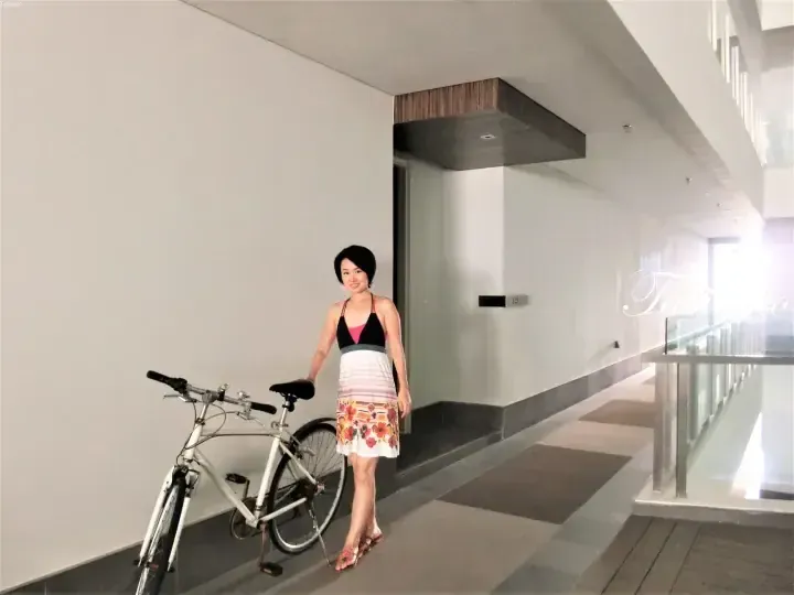 Woman standing with a bicycle in a modern property corridor.