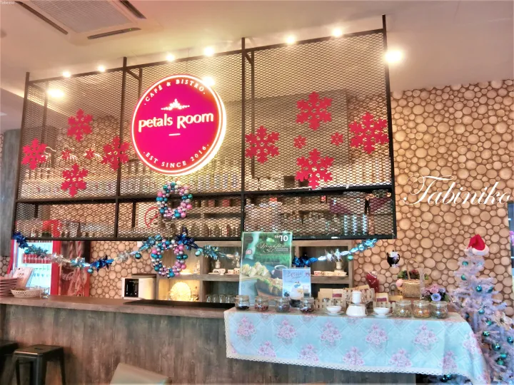 ピンクのネオンサインと木製カウンター、クリスマスの飾り付けが特徴的なPetals Room Cafe & Bistroの店内。