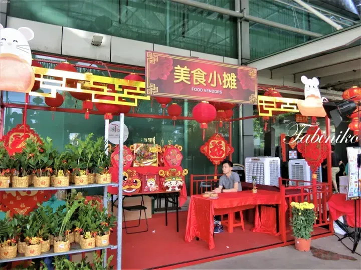 Red lanterns and festive decorations adorn a food vendor stall at a Chinese New Year market.