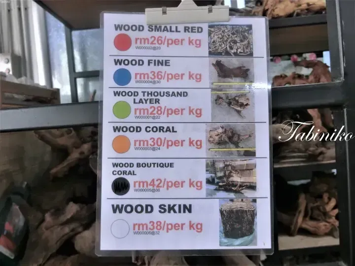 Price list for aquarium driftwood types including Wood Small Red, Wood Fine, and Wood Skin displayed at a Malaysian store.
