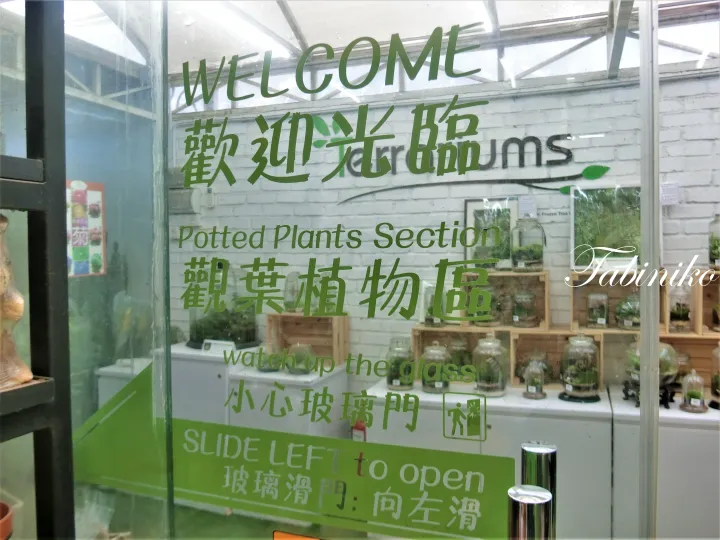 「観葉植物区」の緑色の文字が書かれたガラスドア。Terrariumsの入口で、スライドして左に開けるよう指示されています。