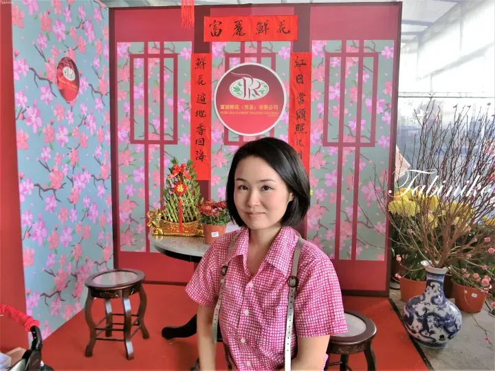身穿粉紅色襯衫的女士在Pudu Ria Florist Trading SDN BHD的節慶裝飾前擺姿勢。