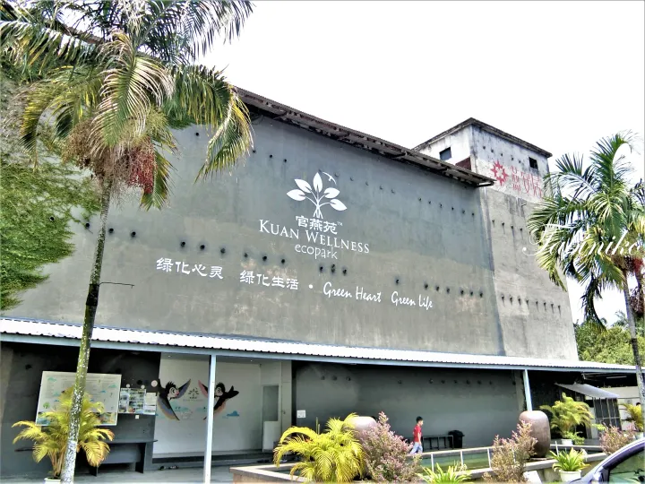 看板と熱帯植物が映るKuan Wellness Ecoparkの建物外観