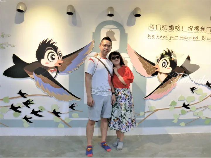 壁のイラストと結婚のメッセージの前でポーズをとるカップル。