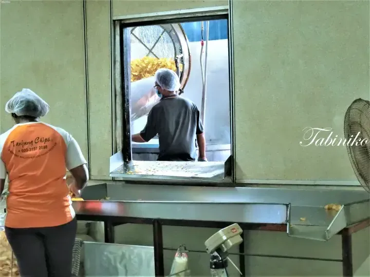 Workers in Tanjung Chips uniforms handling potato chips at the Arowana Malayan Food Industries factory.