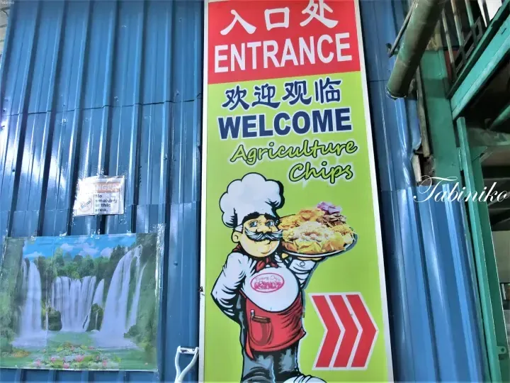 Entrance sign for Agriculture Chips welcoming visitors with a cartoon chef holding a plate of snacks.