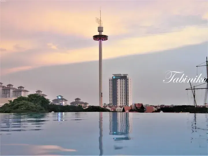 Sunset view from an infinity pool overlooking the Melaka Tower and Holiday Inn in Malaysia.