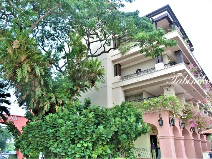 The exterior of Tabiriko hotel in Malaysia, featuring lush greenery, bougainvillea flowers, and a pink arched entrance.