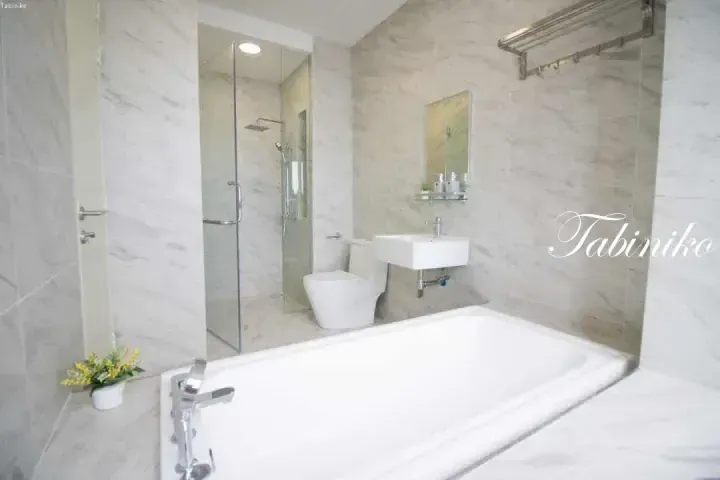 Modern bathroom with marble tiles, glass shower, bathtub, and sink at Tabiniko property.