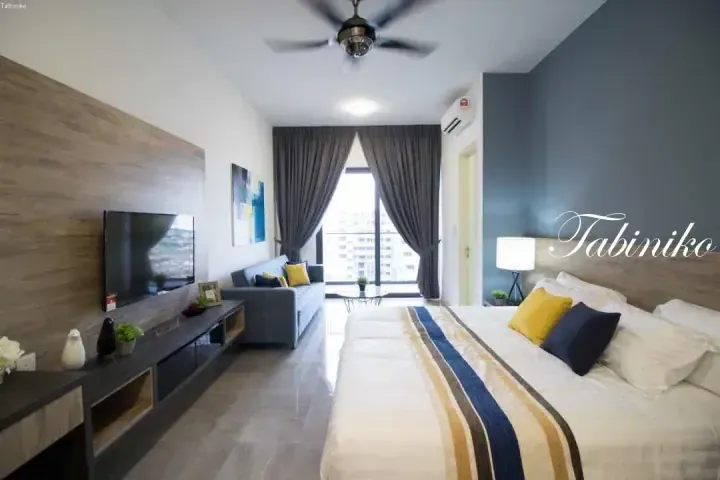Modern serviced apartment interior with a king bed, living area, and balcony view at Tabiniko.