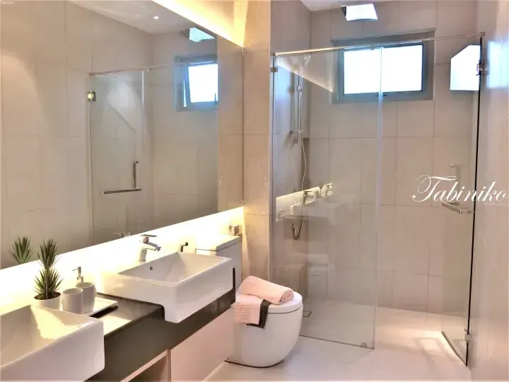 Modern bathroom with double sinks, glass shower enclosure, and beige tiles