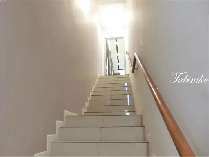 Modern white tiled staircase with wooden handrail leading to upper floor in a contemporary Malaysian property.