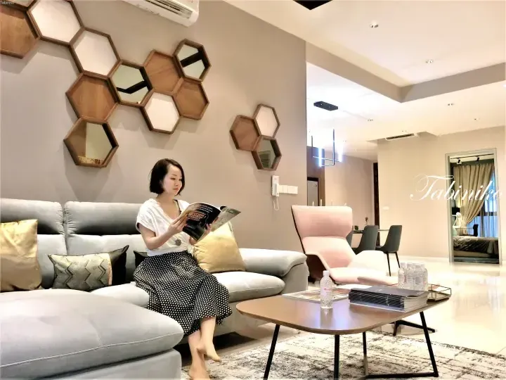 Woman reading a magazine in a modern showroom featuring honeycomb wall decor and a grey sofa.