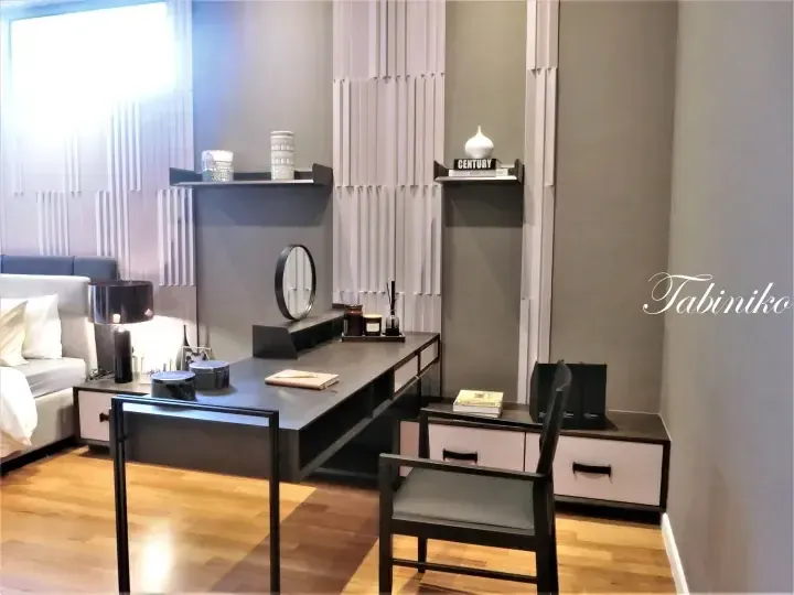 Modern bedroom featuring a sleek black desk with a round mirror, white drawers, and a black chair in a contemporary setting.