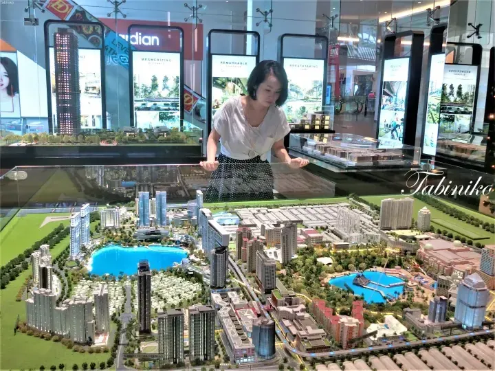 Woman examining a large architectural model of Sunway Geo Residences and Sunway Lagoon in a showroom display.