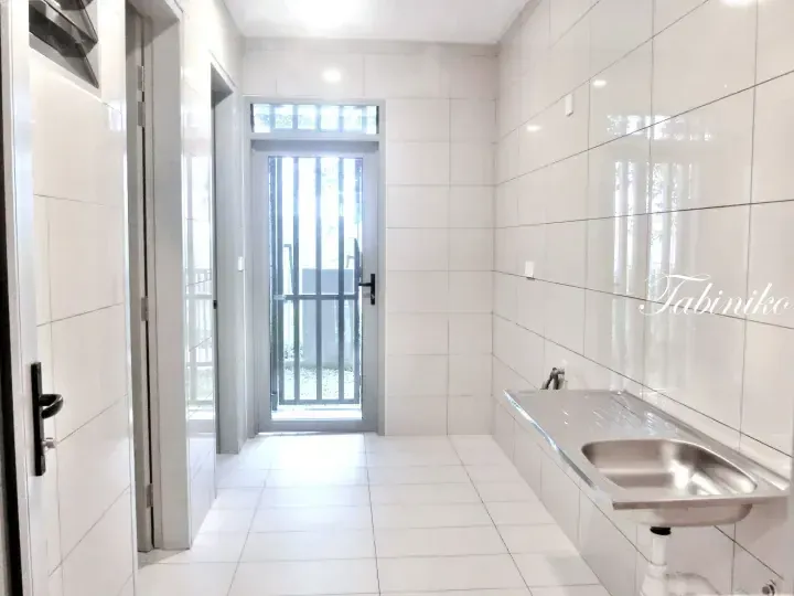 Bright modern kitchen with white tiles, stainless steel sink, and a glass door leading to an outdoor area.