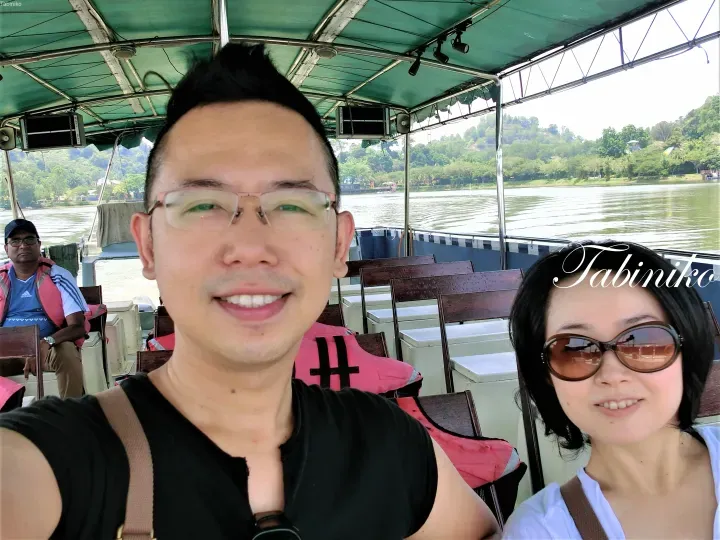 Couple smiling on a boat tour with river and green hills in the background.
