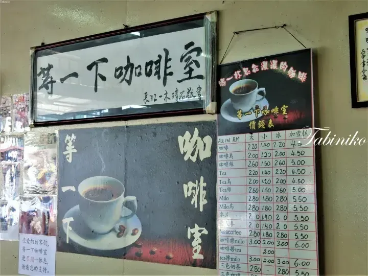 Menu board and sign at Wait Yi Xia Coffee Room displaying prices for coffee, tea, and Milo in Malaysian Ringgit.