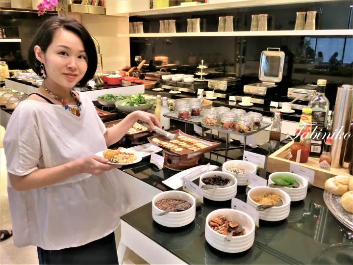 ナッツやシードが並ぶビュッフェの料理棚で食事を選ぶ女性。