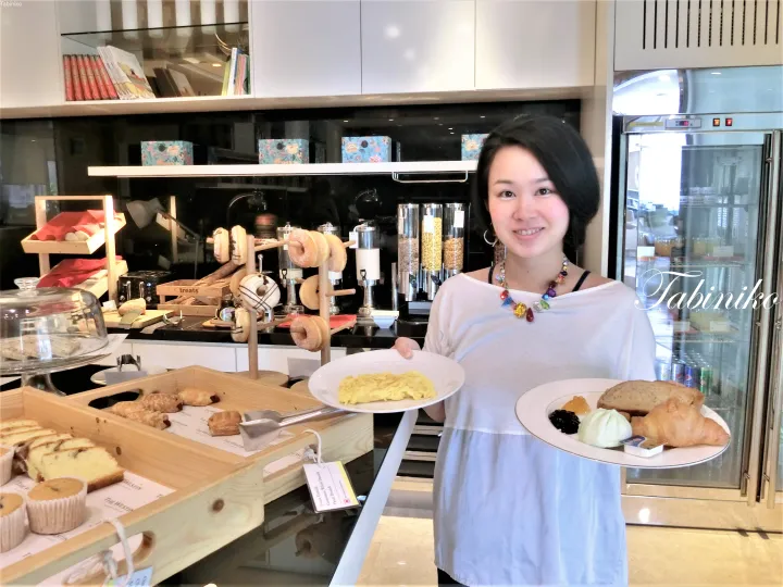 ザ・ウェスティンでドーナツやオムレツが並ぶビュッフェで朝食の皿を持つ女性。