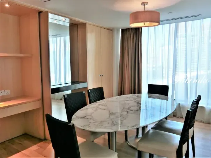 Modern dining area with marble table and black chairs in a serviced apartment, featuring built-in wooden cabinetry and large windows.