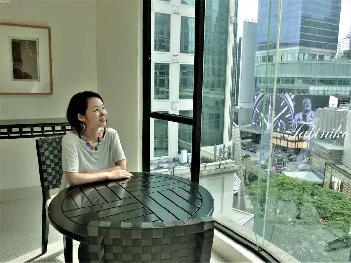 Woman relaxing on a balcony with a city view, overlooking the busy streets and modern buildings of Kuala Lumpur.