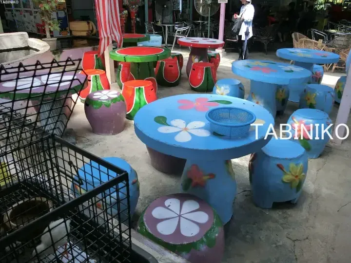 Colorful concrete tables and stools painted with flowers and watermelons at an outdoor seating area.