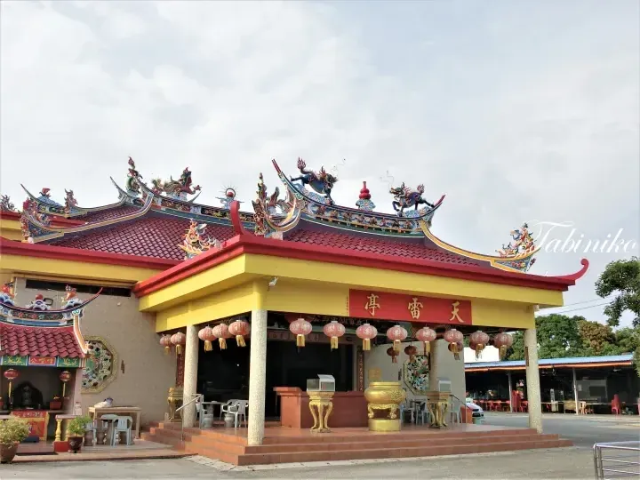 Tian Lei Ting temple exterior featuring a vibrant yellow facade, red tiled roof with dragon sculptures, and hanging lanterns.