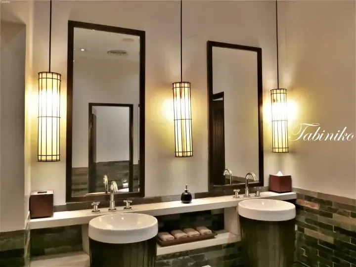 Elegant bathroom with two white vessel sinks, dark green tiles, and warm pendant lights at a luxury property.