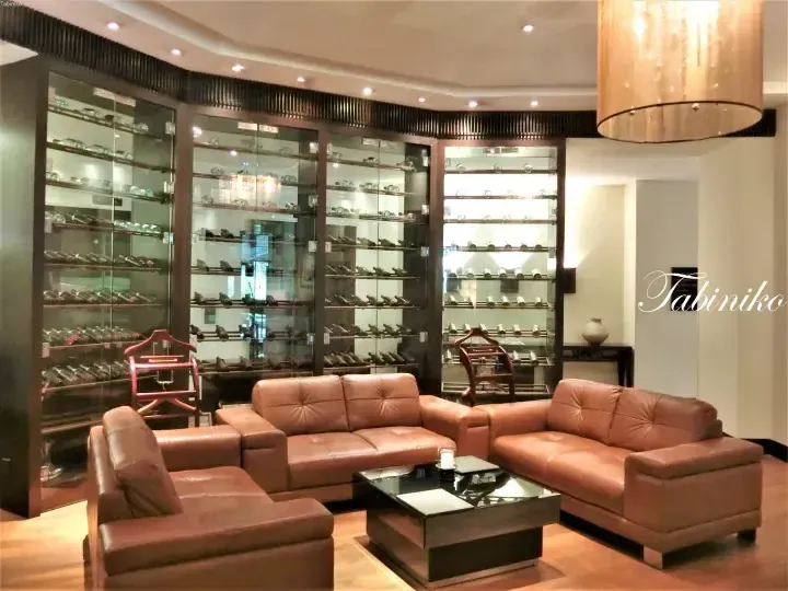 Luxury wine cellar with glass display cabinets and brown leather sofas in a modern lounge area