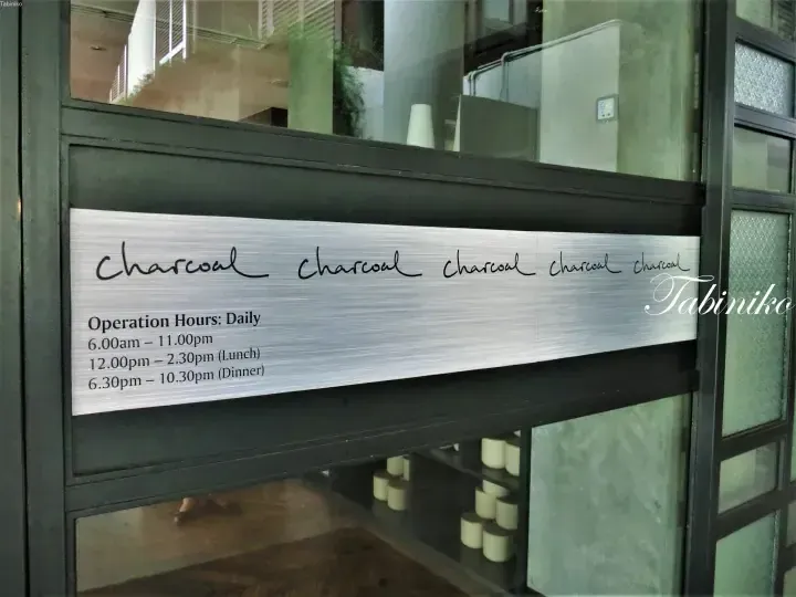 Brushed metal sign with handwritten “Charcoal” and operation hours for a restaurant.