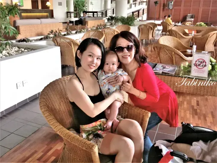 A family posing in the lounge of The Saujana Hotel, featuring wicker furniture and a ‘Say NO to STRAW’ sign.