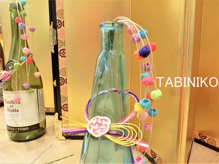 Casillero del Diabloのワインボトルと共に展示された、Tabinikoブランドのカラーフルなマクラメボトルデコレーション。