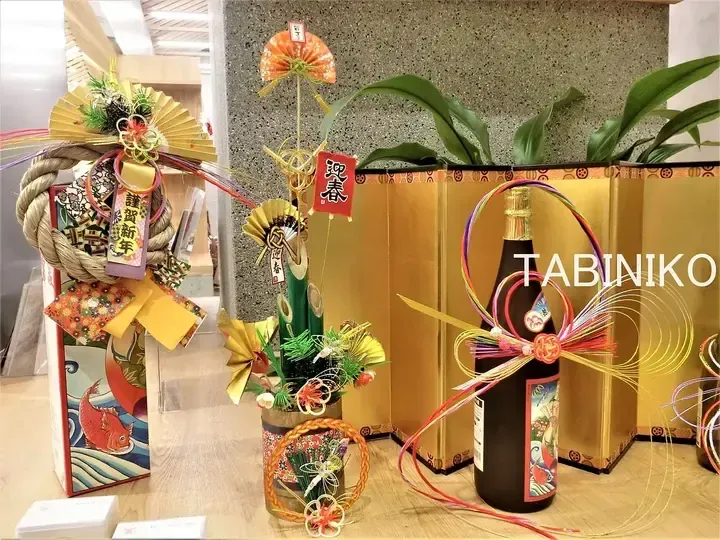Traditional Japanese New Year decorations including kadomatsu, shimekazari, and sake bottles displayed in a modern interior setting.