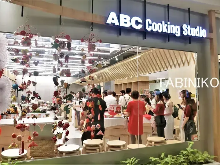 ABC Cooking Studio storefront with colorful hanging decorations and customers inside.