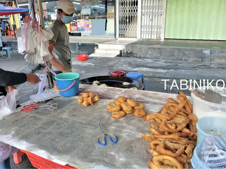 屋台で伝統的な揚げ菓子や胡麻付きドーナツを販売する屋台の風景。