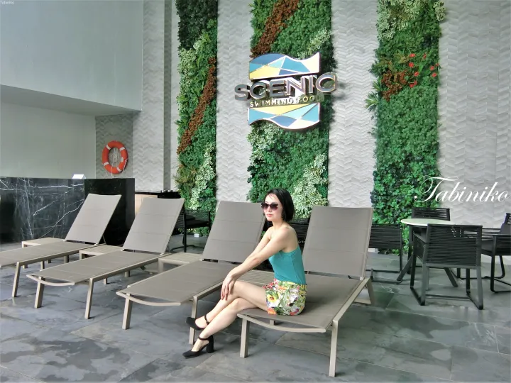 グリーンウォールを背景にScenic Swimming Poolのラウンジチェアに座る女性。