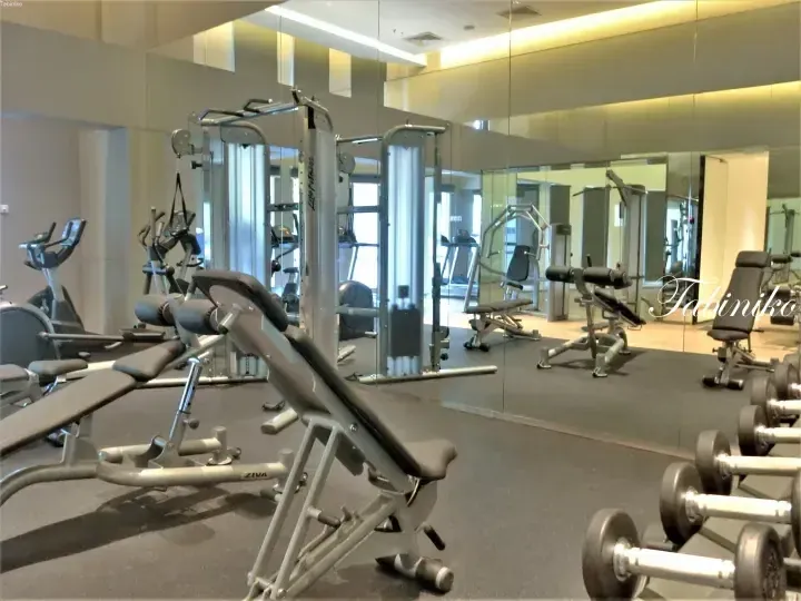 Well-equipped hotel gym featuring ZIVA weight benches, cable machines, and dumbbells in a bright mirrored space