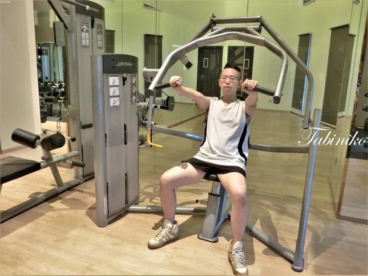 鏡張りのモダンなジムでLife Fitnessのチェストプレスマシンを使用する男性。