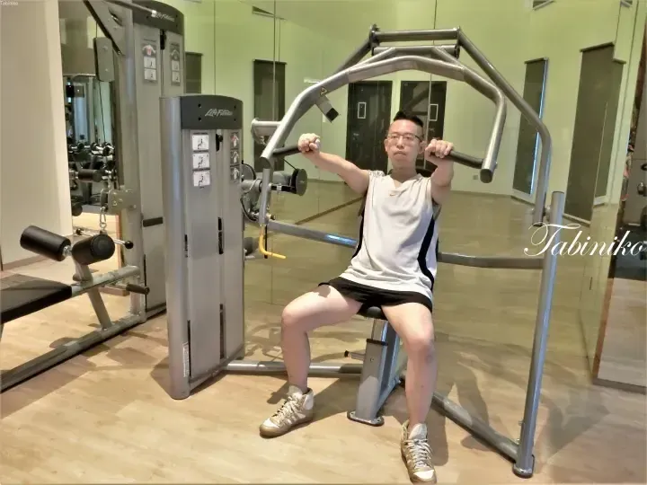Man exercising on a Life Fitness chest press machine in a modern gym with mirrored walls.