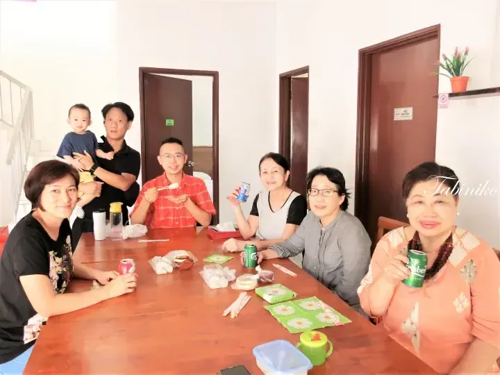 A group of friends enjoying a meal together at a wooden dining table inside a property.
