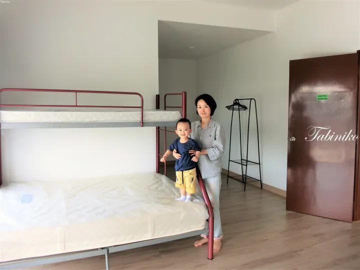 二段ベッドと「MASTER BEDROOM」の標識がある部屋で微笑む女性と幼児。
