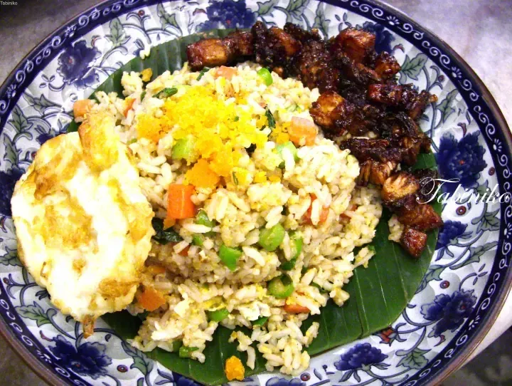Nasi kerabu with fried egg and sambal belacan served on a banana leaf in a blue floral plate