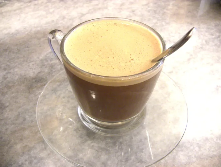 マレーシアのカフェで提供される、スプーン付きガラスマグの泡立つコーヒー