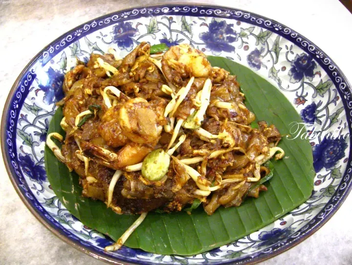 A plate of Penang Char Kway Teow with shrimp, bean sprouts, and Chinese sausage served on a banana leaf