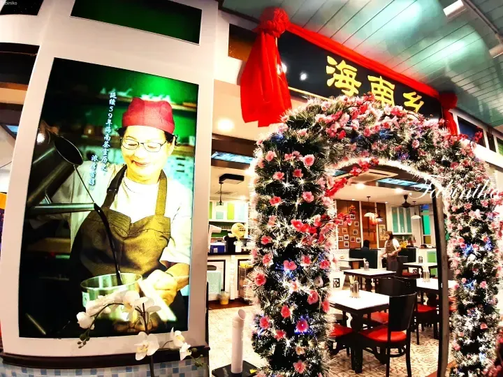 Restaurant entrance with festive Christmas tree arch and large poster of a tea maker at Hainan Xiang.